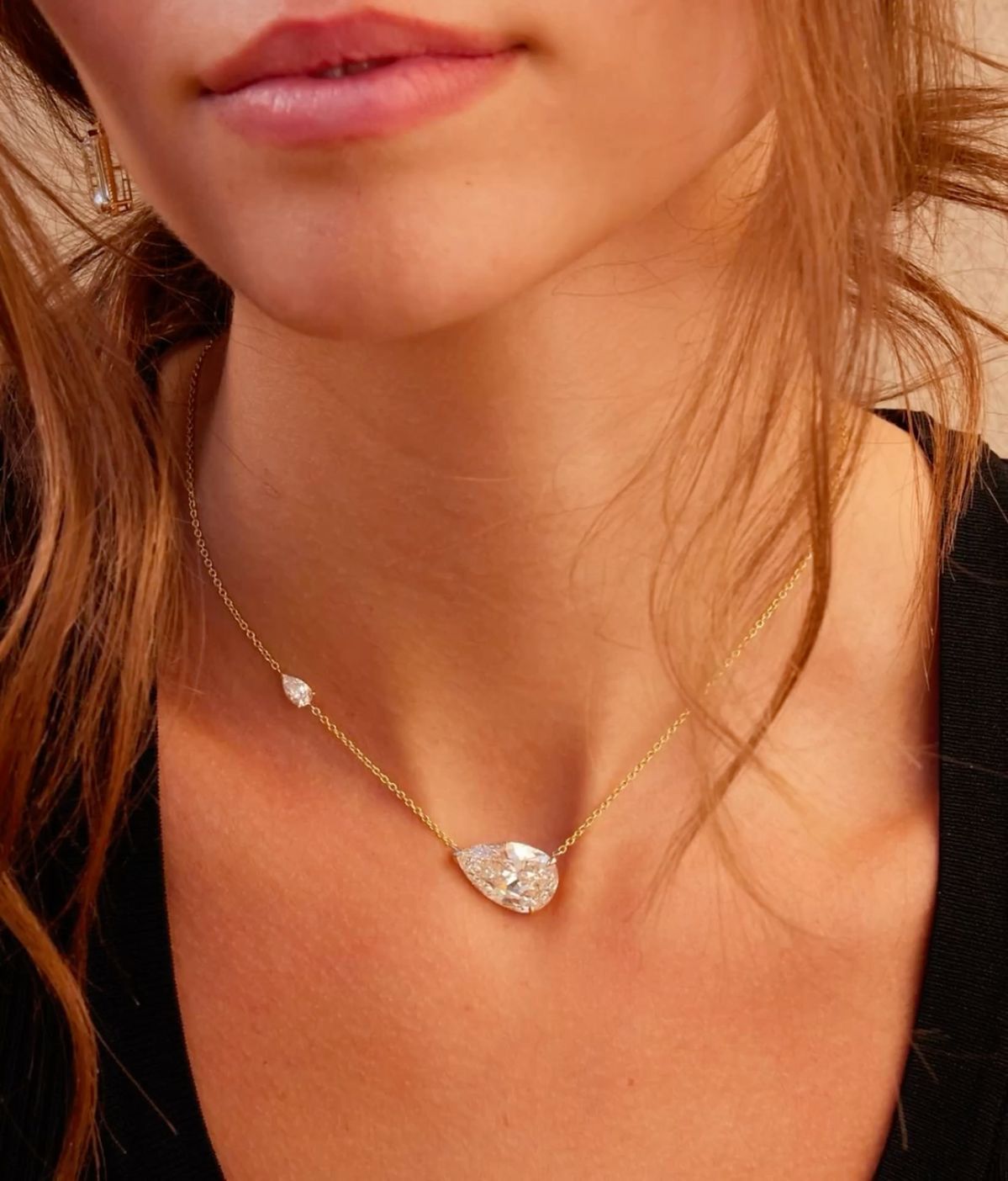 A fine chain necklace with a round center pendant and a pale square accent.