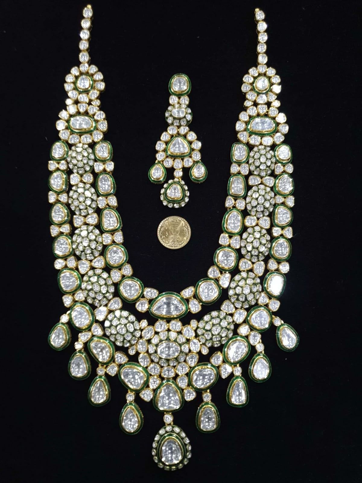 A broad pale necklace with a green-toned center drop and matching earrings.