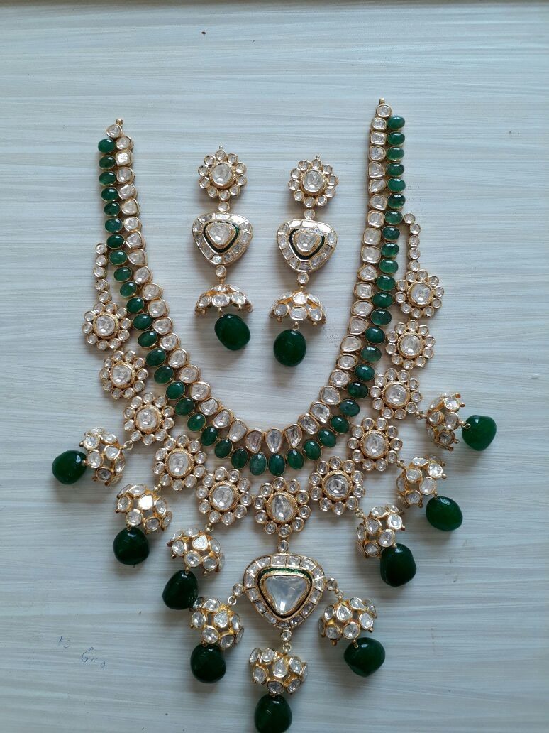 A coordinated display of necklace, earrings, and bracelet with green-toned drops.