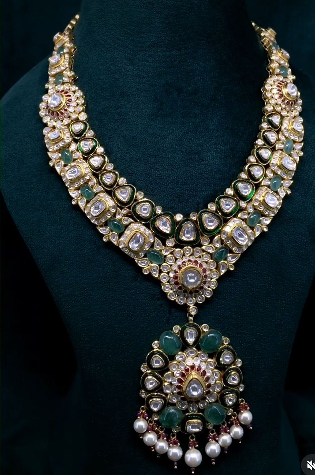 A necklace with a large green-toned framed pendant and matching earrings.
