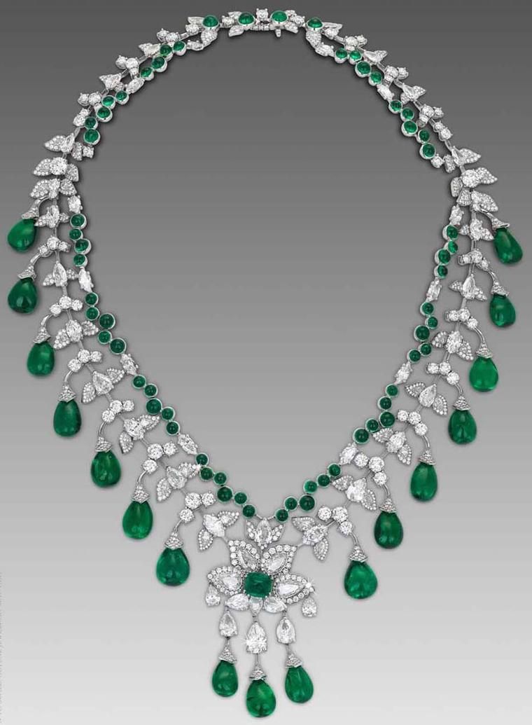 A curved necklace with green-toned drops and a floral center detail.