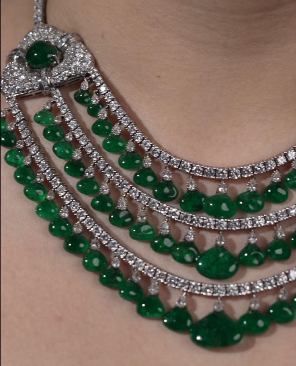 Several close-set necklace rows with green-toned drops, shown worn at the neckline.