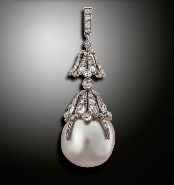 A long drop earring with a pale round end and layered details.