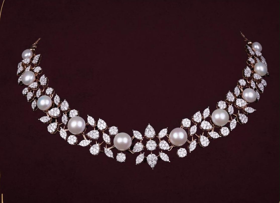 A curved necklace with pale flower-shaped details on a dark red display.