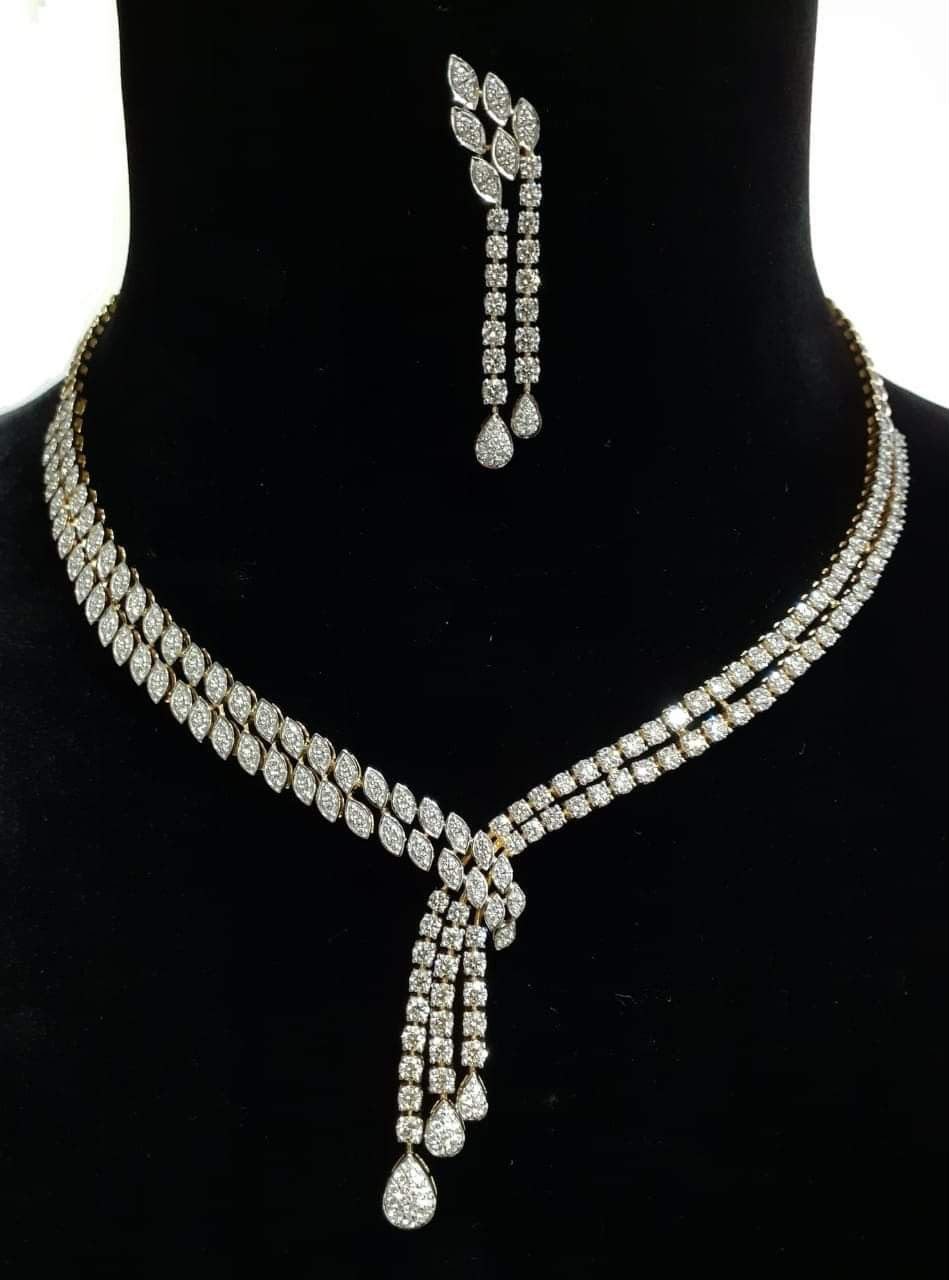 A pale necklace with a long center drop and matching earring shown above it.