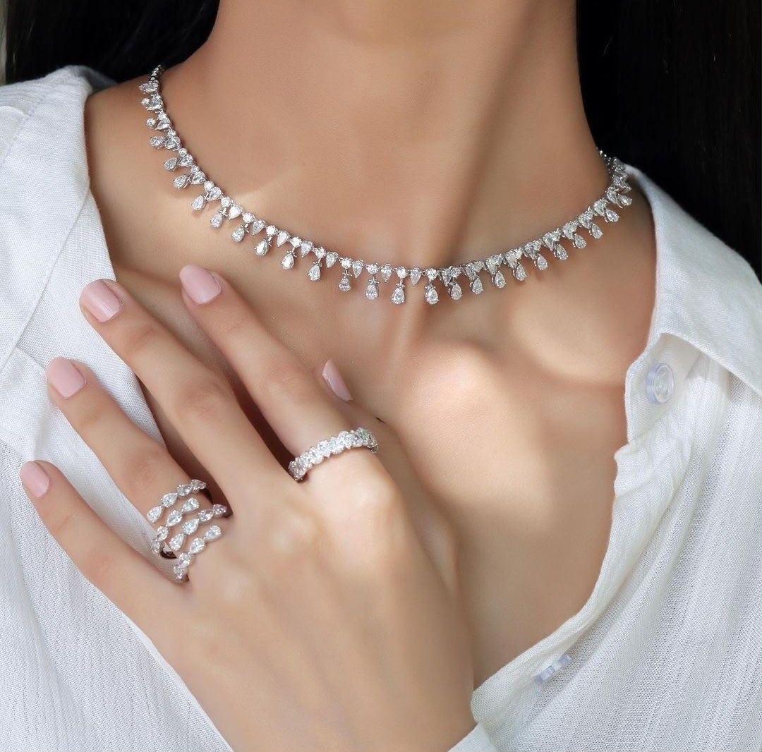 A necklace and matching ring with pale floral details, shown worn.