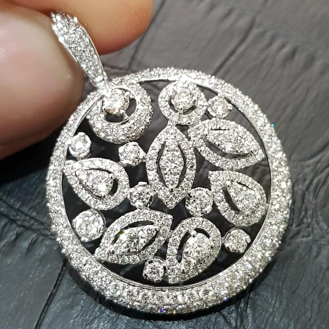 A round pendant with open floral shapes and a pale border.