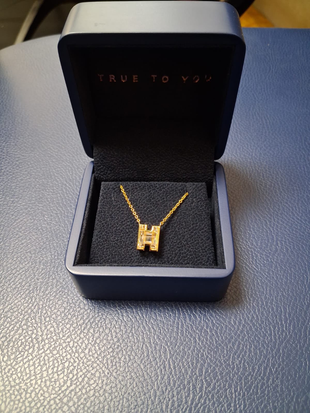 A fine necklace with a square pendant shown in a presentation box.