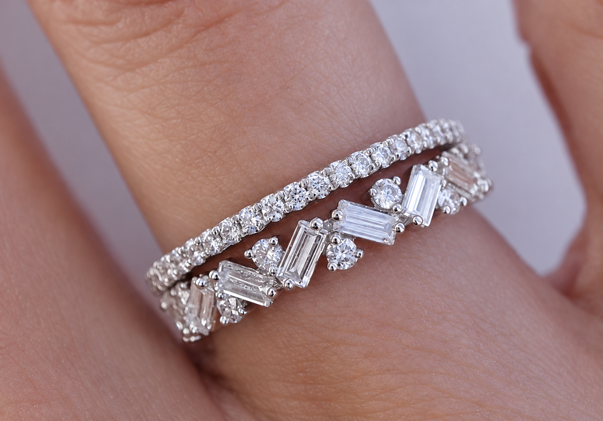 The photograph pairs a slender round-stone band with an angular arrangement of rectangular and round accents.