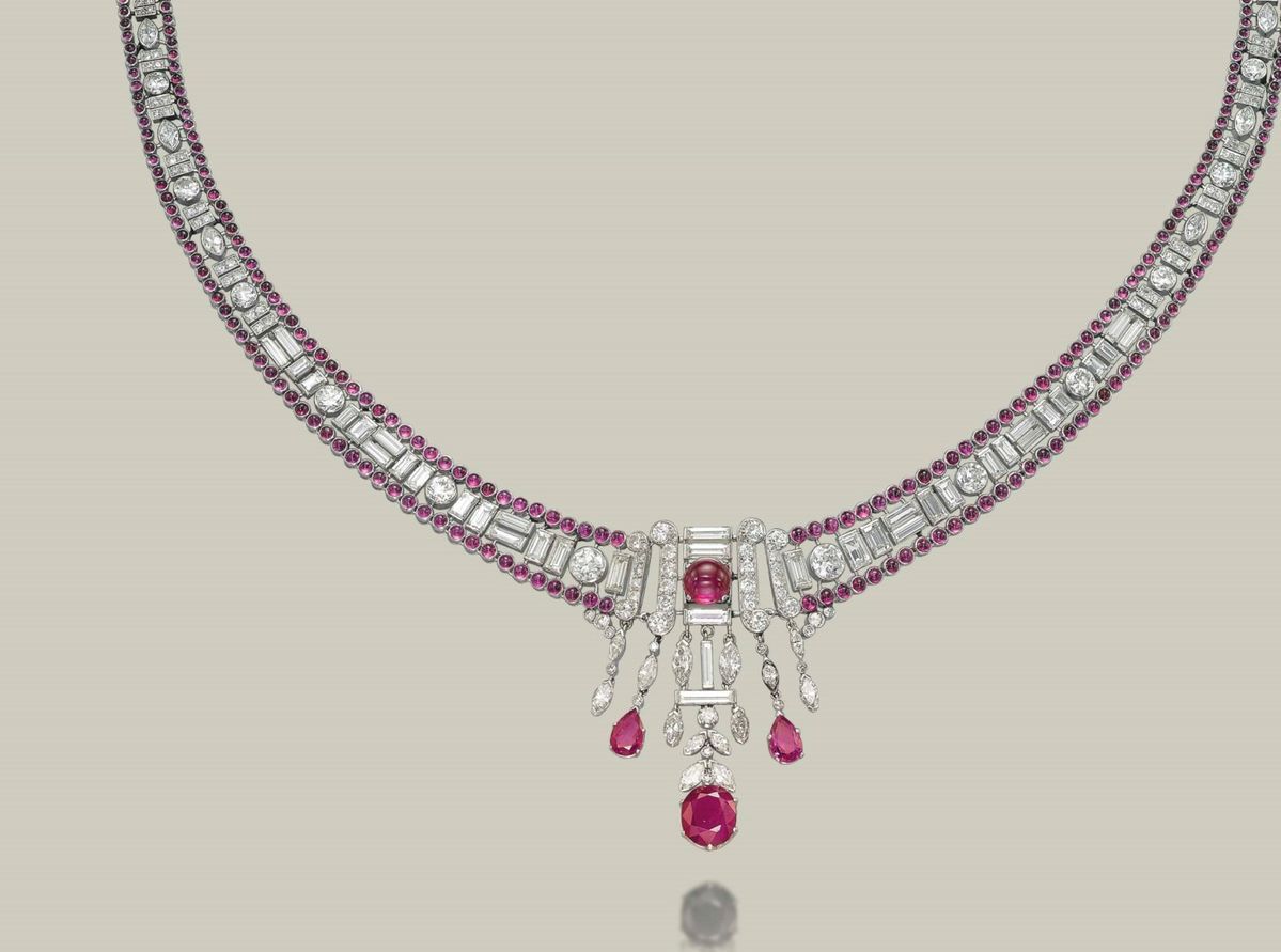 a curved necklace with a pink-toned center drop