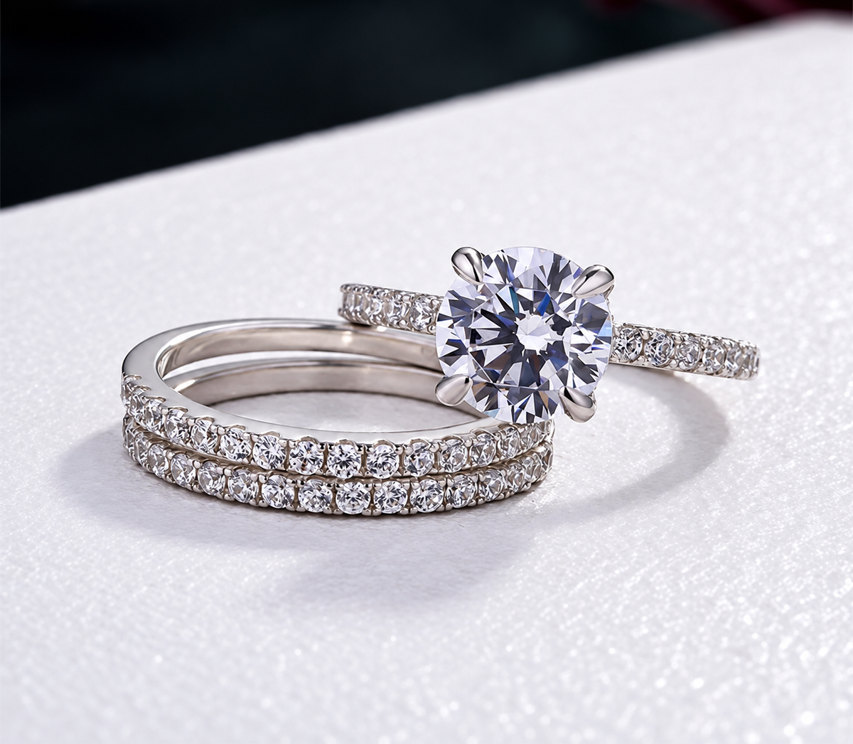 A round clear centre crowns a slender sparkling ring paired with two matching stone-lined bands.