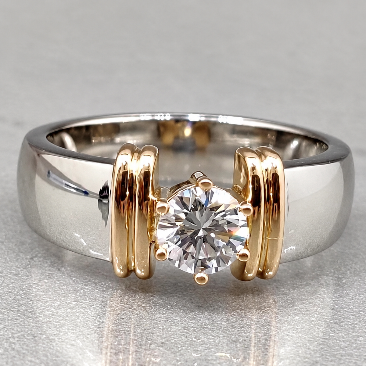 A round clear centre stands between paired yellow-coloured pillars on a broad silver-coloured band.
