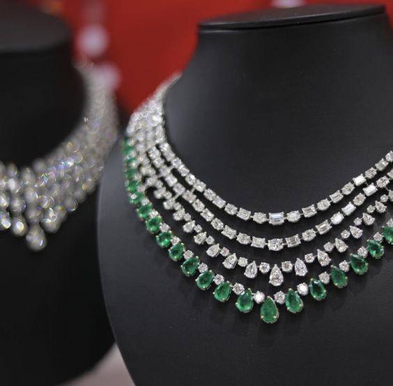 Several close-set necklace rows with green-toned accents on a dark display.