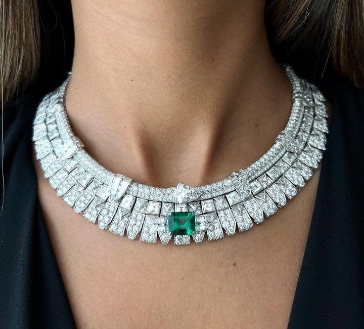 A broad necklace with geometric panels and green-toned accents.