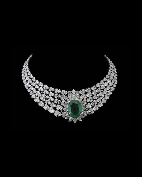 A broad pale necklace with a green-toned oval center detail.
