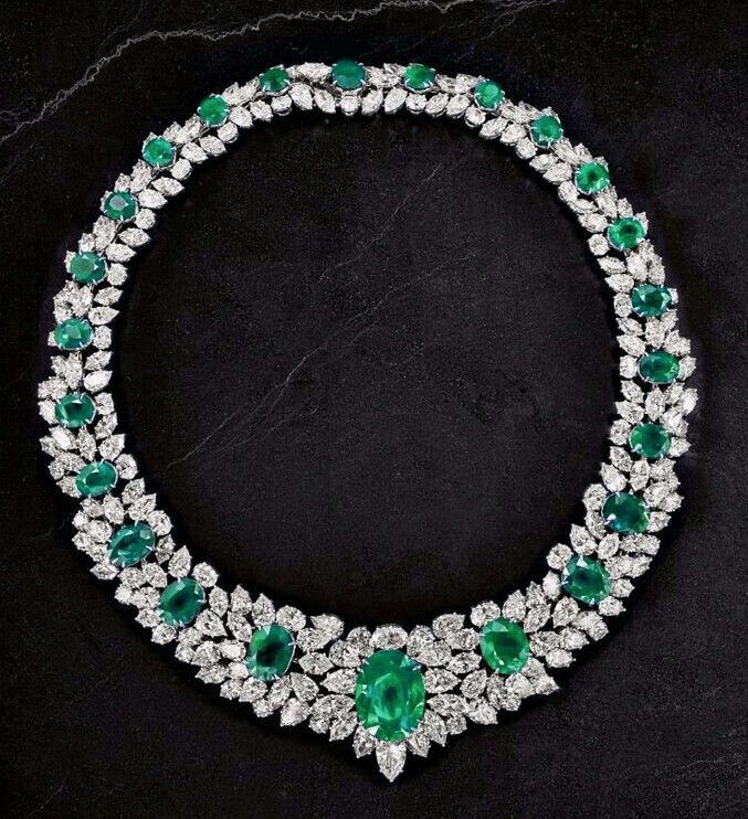 A rounded necklace design with green-toned floral details and a center drop.