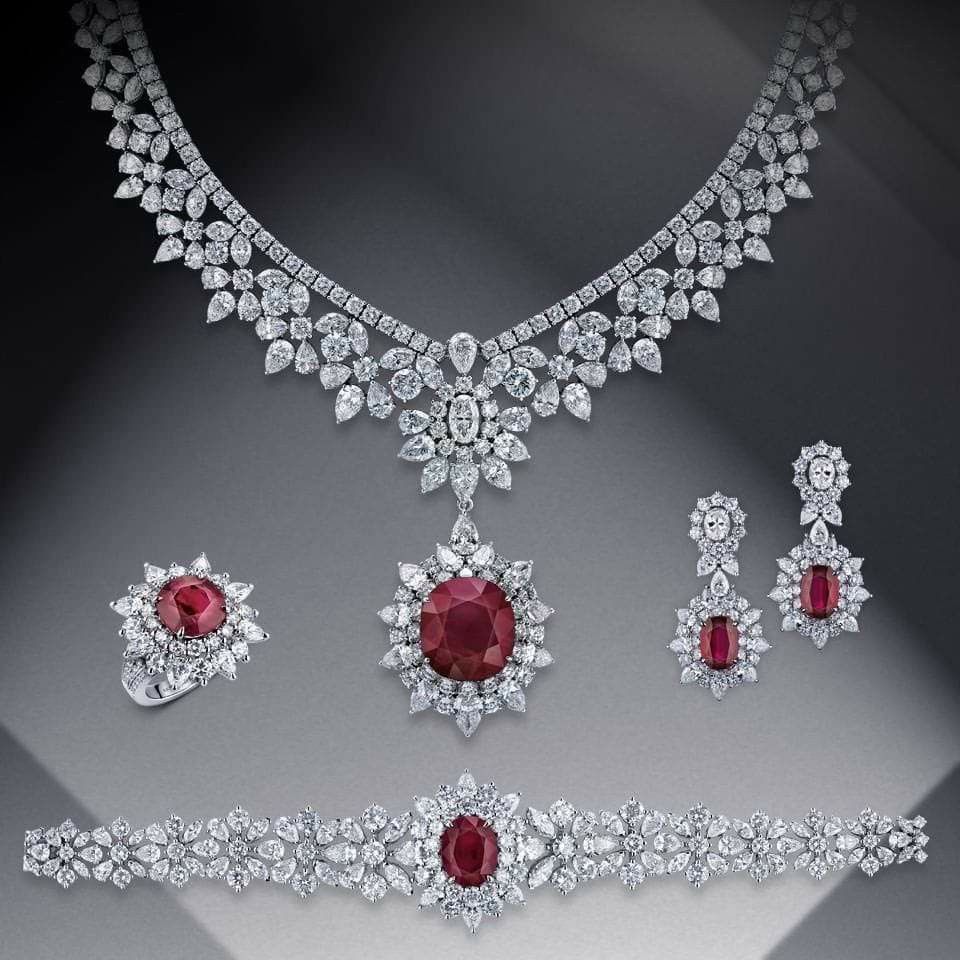 A coordinated arrangement of necklace, earrings, and bracelets with red and green-toned details.