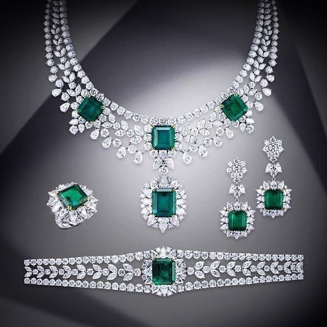 A coordinated display of necklace, earrings, bracelet, and ring with green-toned panel details.