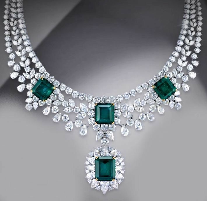A necklace with a rectangular green-toned center pendant and matching drop details.