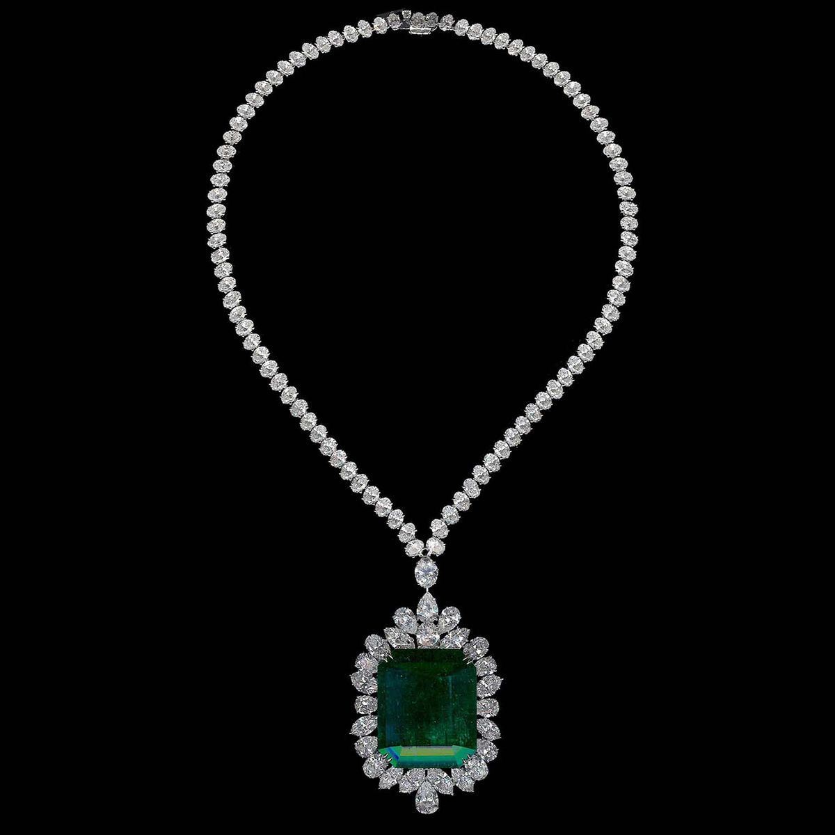 A fine necklace with a square green-toned pendant and a small drop below.