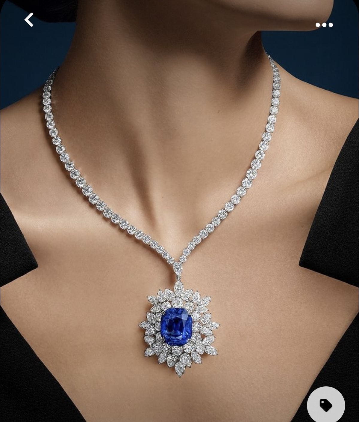 A fine necklace with a blue-toned center pendant in a pale floral frame.