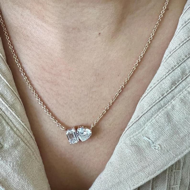 A fine chain necklace with a small blue-toned heart-shaped pendant.