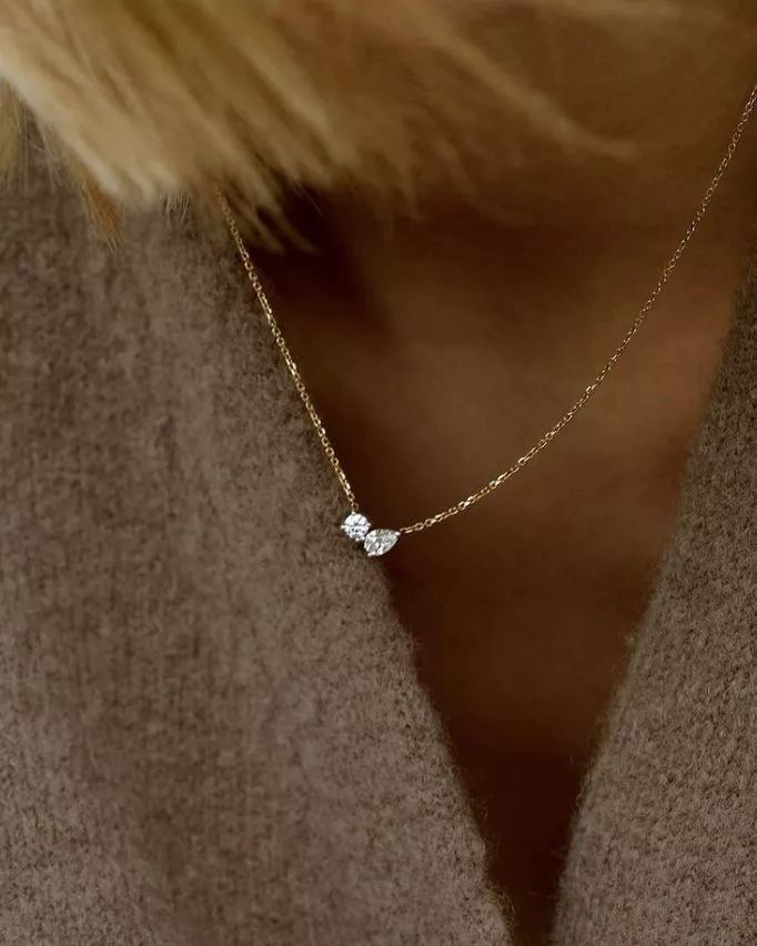 A fine chain necklace with a small pale flower-shaped pendant.