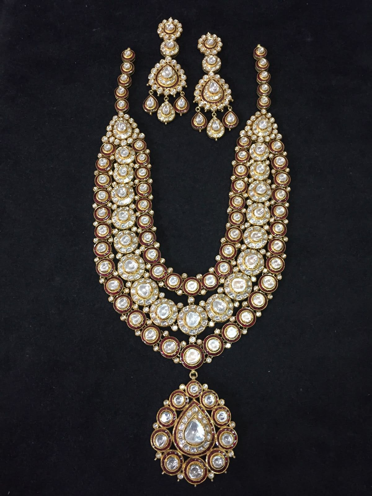 A long pale necklace with a large teardrop-shaped center pendant and matching earrings.