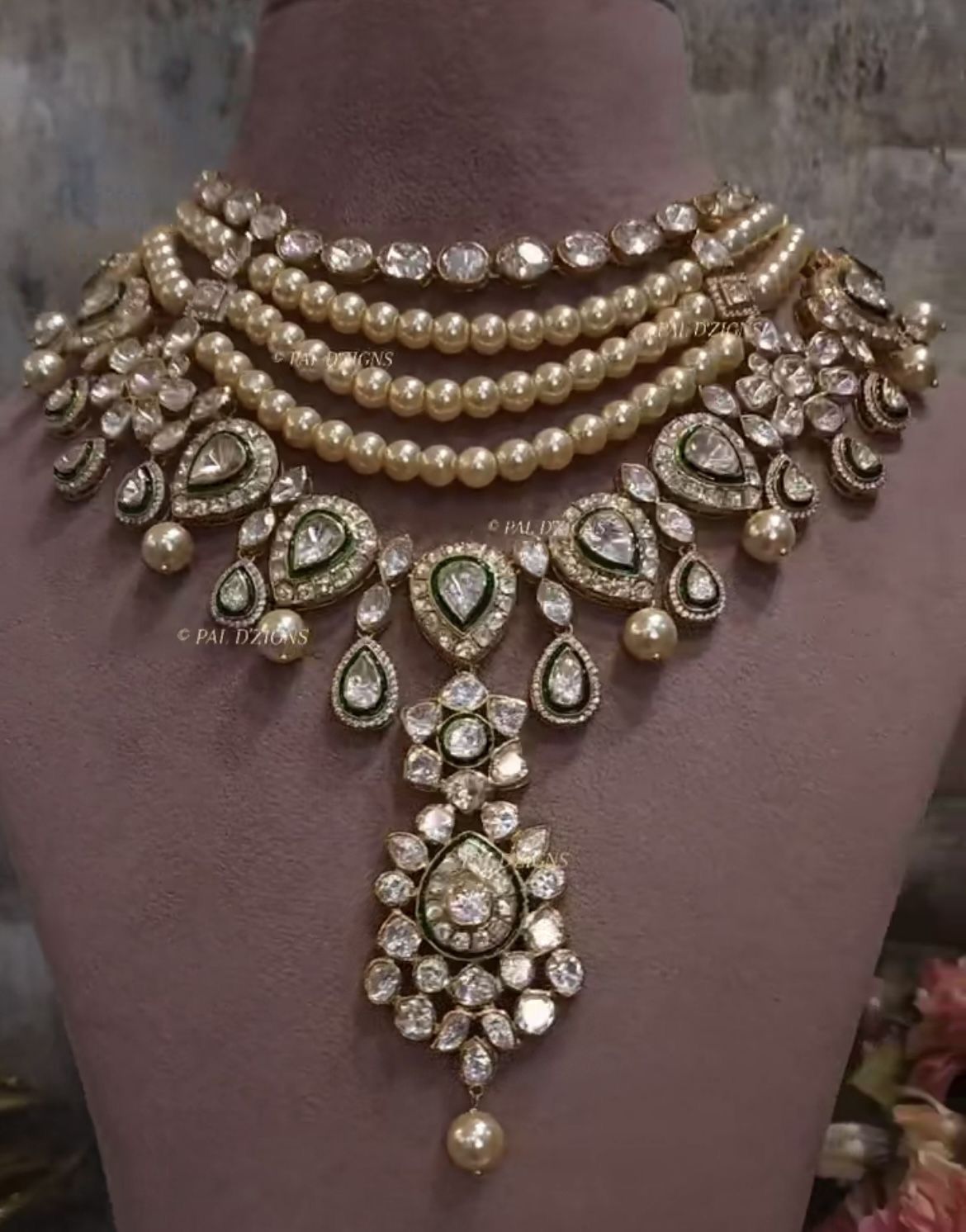 A multirow necklace with pale and warm-toned details and a large center drop.