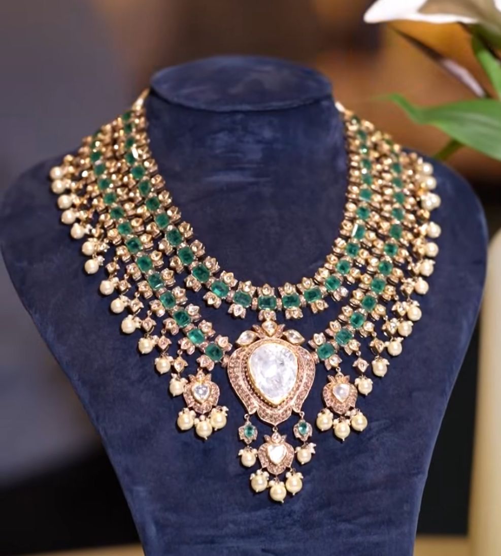 Several layered necklace rows with green and blush-toned details.