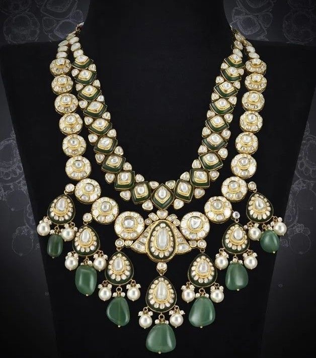 A broad necklace with pale round motifs and green-toned drops.