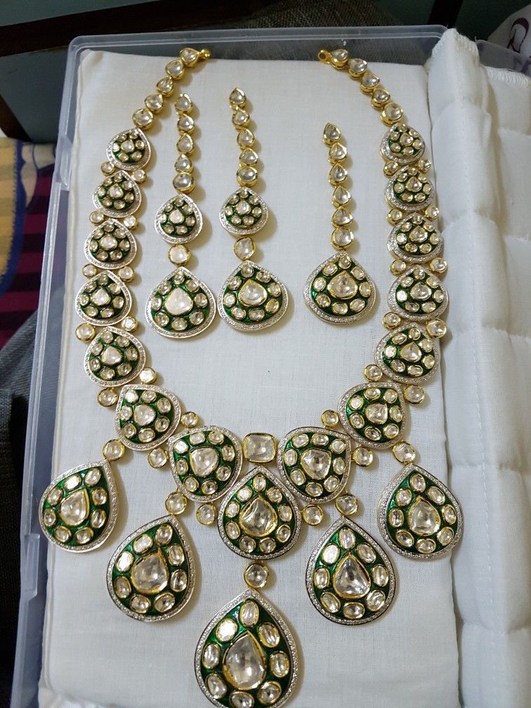 A coordinated display of necklace and matching pieces with green-toned floral details.