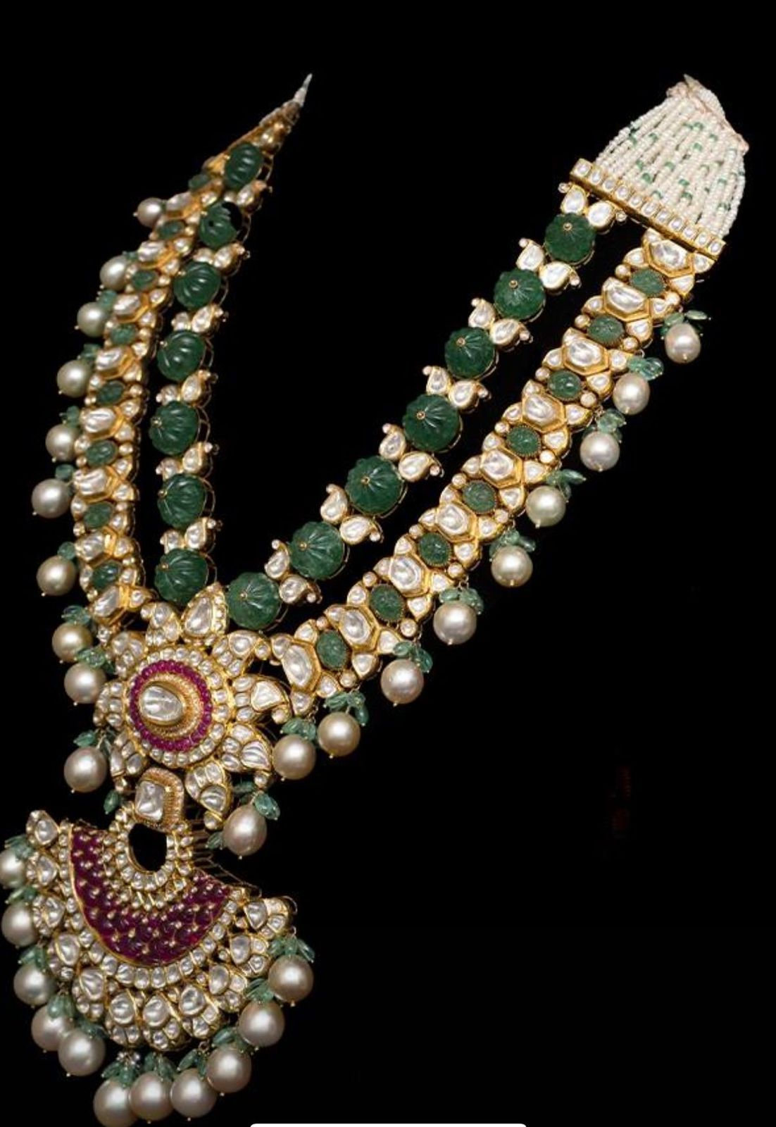 A long, layered necklace with green and warm-toned accents and a large center drop.