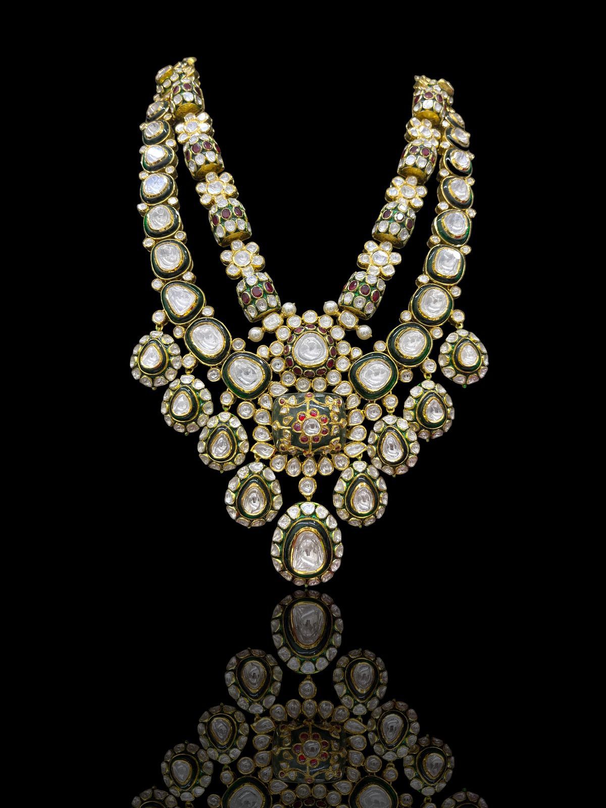 A broad pale necklace with a green-toned center drop and matching earrings.