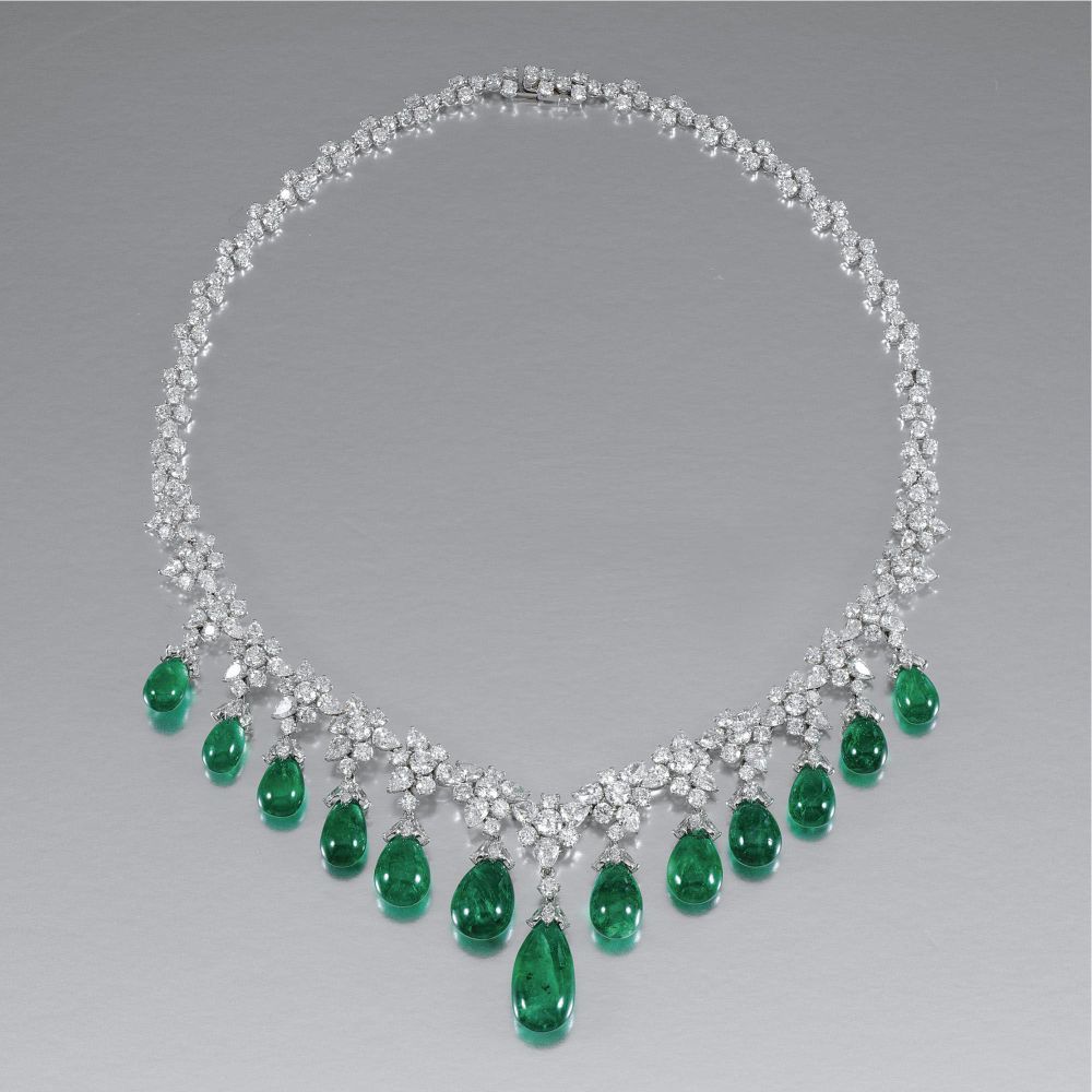 A curved necklace with pale details and green-toned drops along the lower edge.