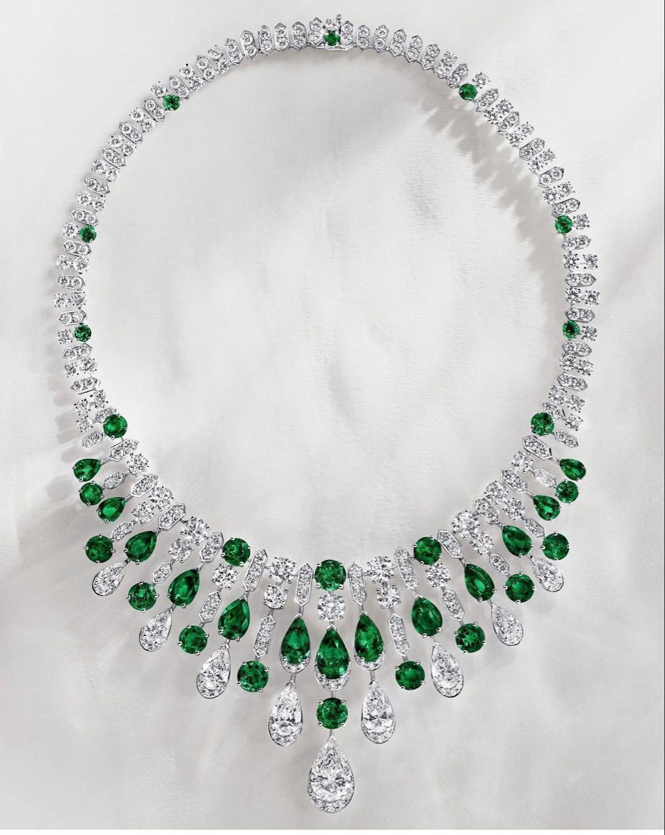 A broad pale necklace with green-toned teardrop details and a center drop.