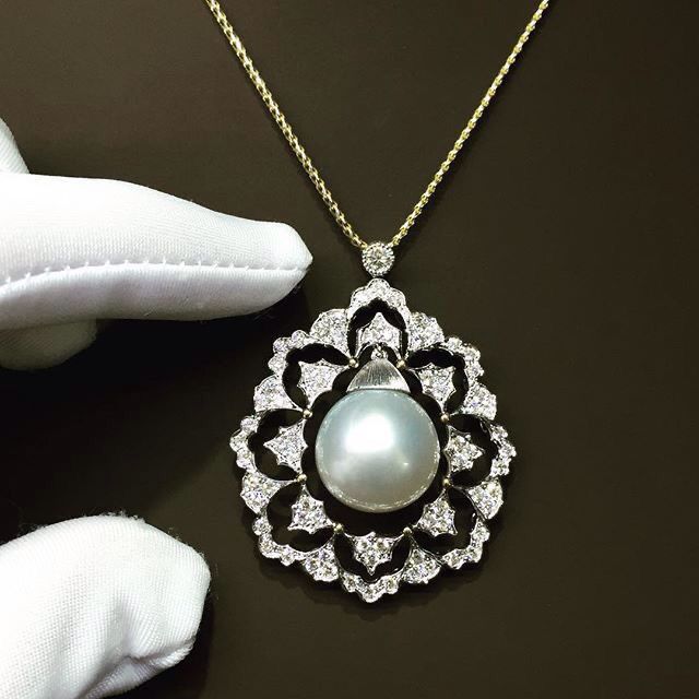 A fine necklace with a large pale round center in a floral frame.