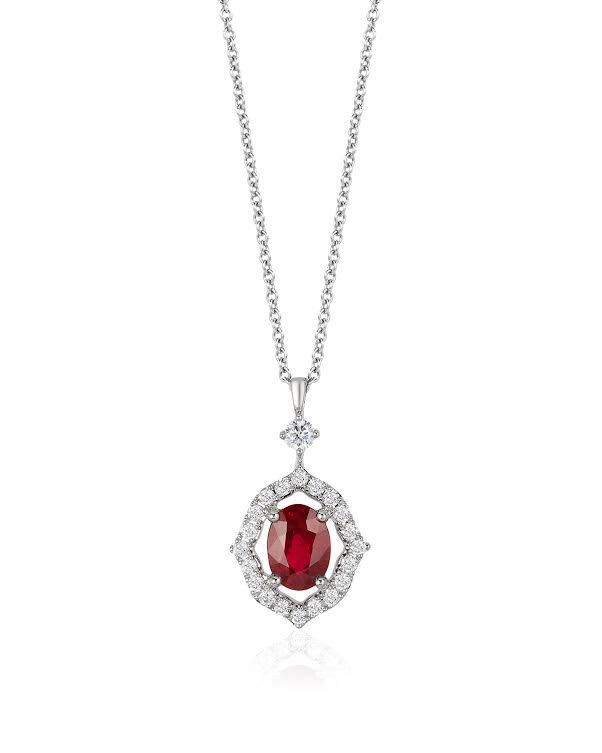 A fine chain necklace with a red-toned oval pendant in a pale frame.