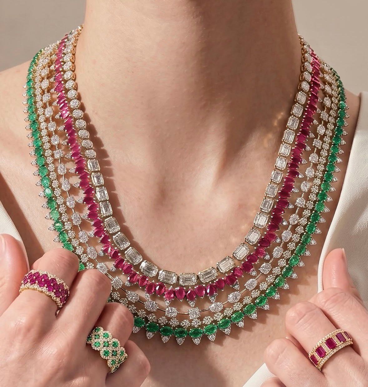 Several close-set necklace rows with green and pale accents.