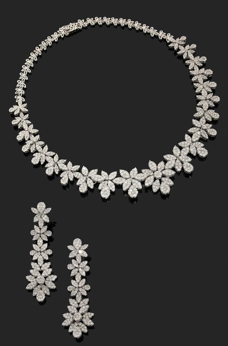 A necklace with pale daisy-shaped details, shown with matching drop earrings.