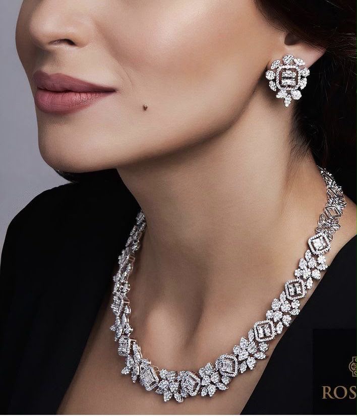 A necklace with repeating floral details, shown with matching earrings.