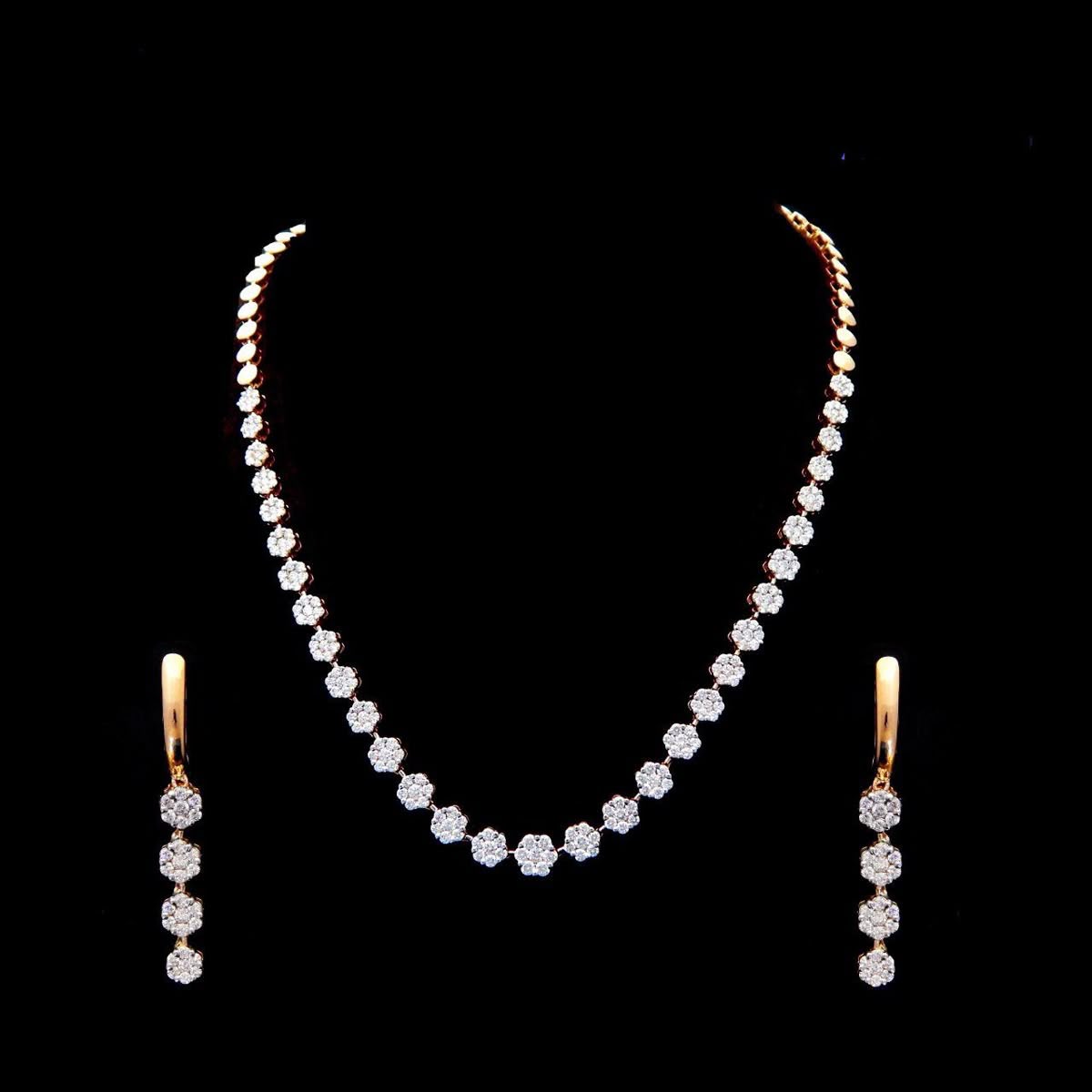 A long necklace with matching drop earrings on a dark display.