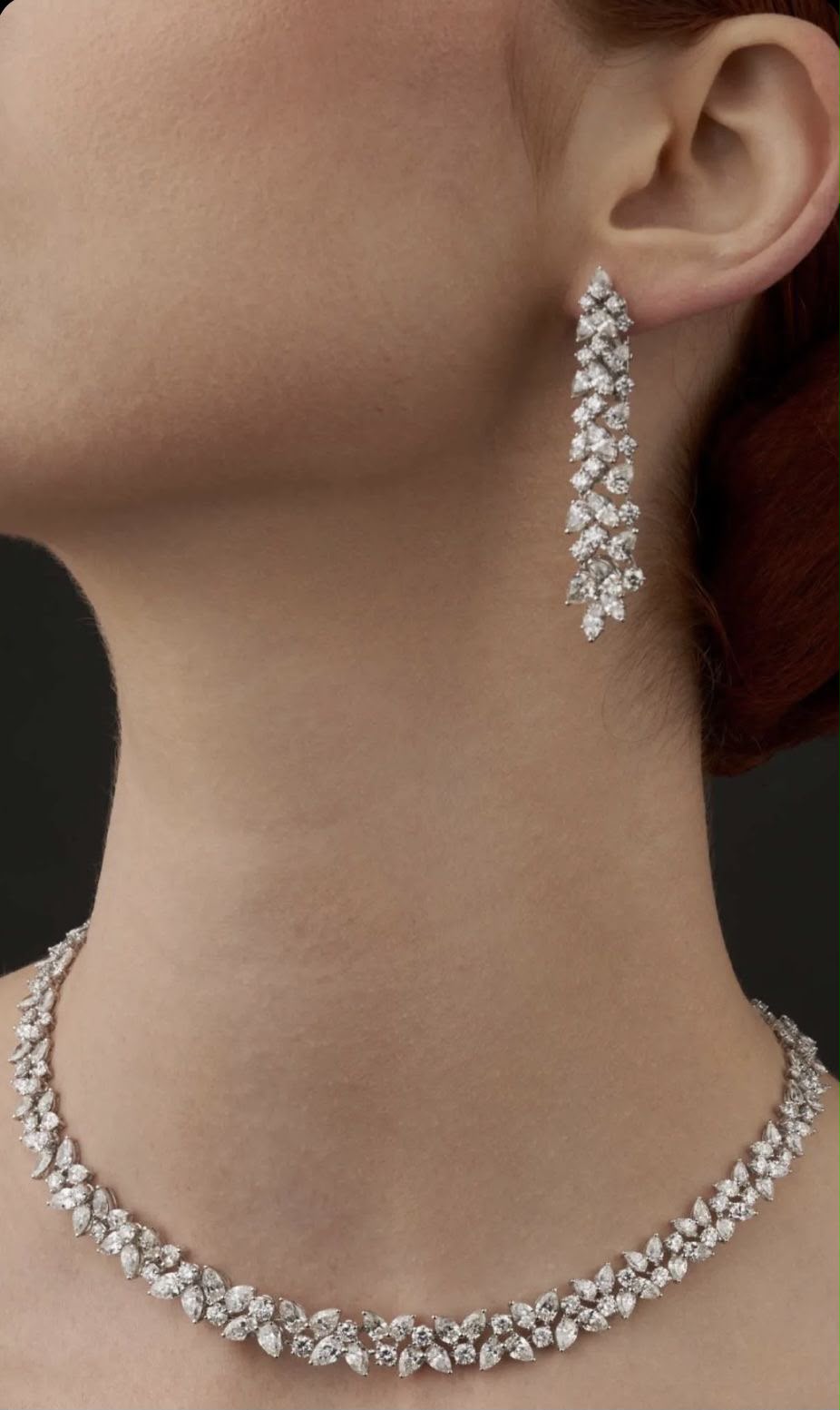 A curved necklace with matching long drop earrings, shown worn.