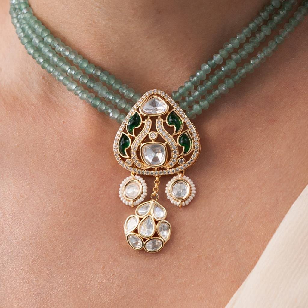 Several green-toned strands meet at a large pendant with pale hanging details.