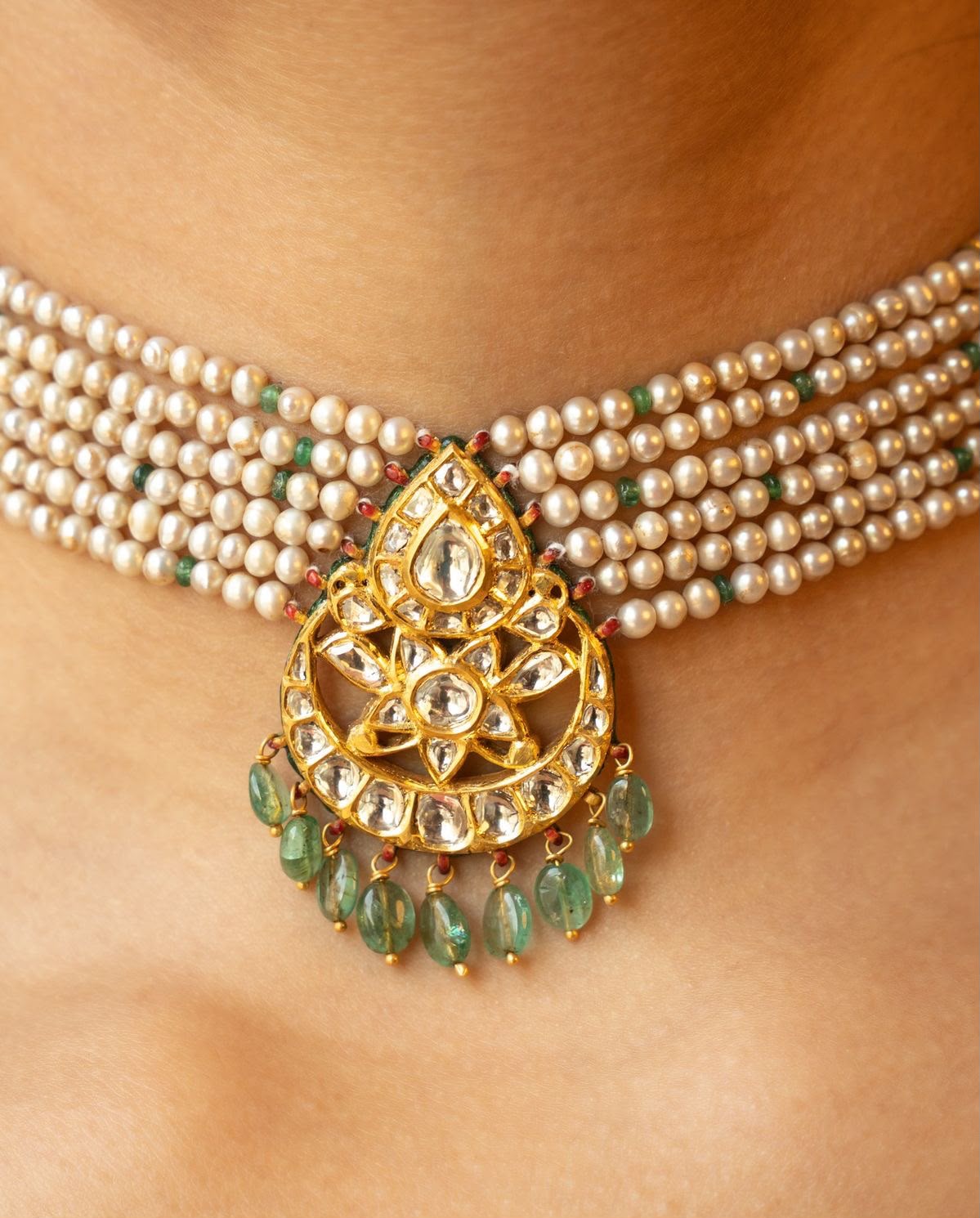 A short multirow necklace with a large framed drop and several hanging details.