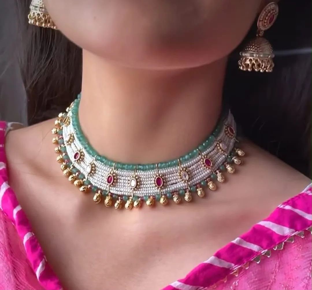 A short pale necklace with small colored accents, shown with a matching earring.