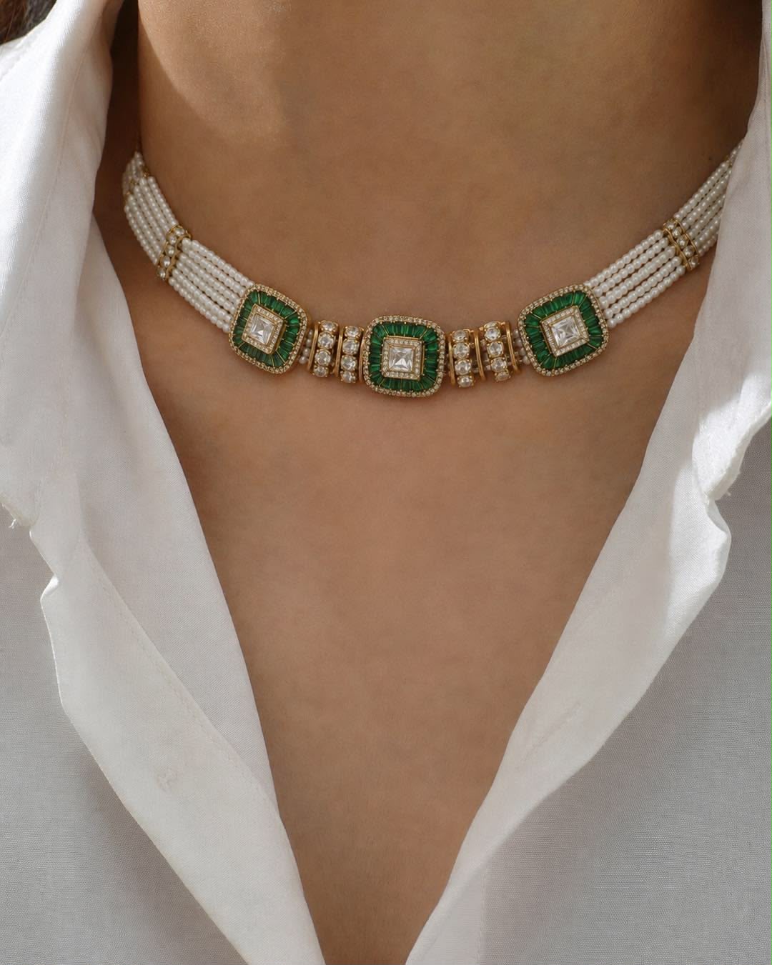 A pale collar necklace with a row of green-toned rectangular accents.