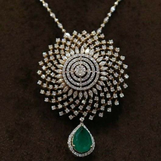 A necklace with a round pale medallion and a green-toned hanging drop.