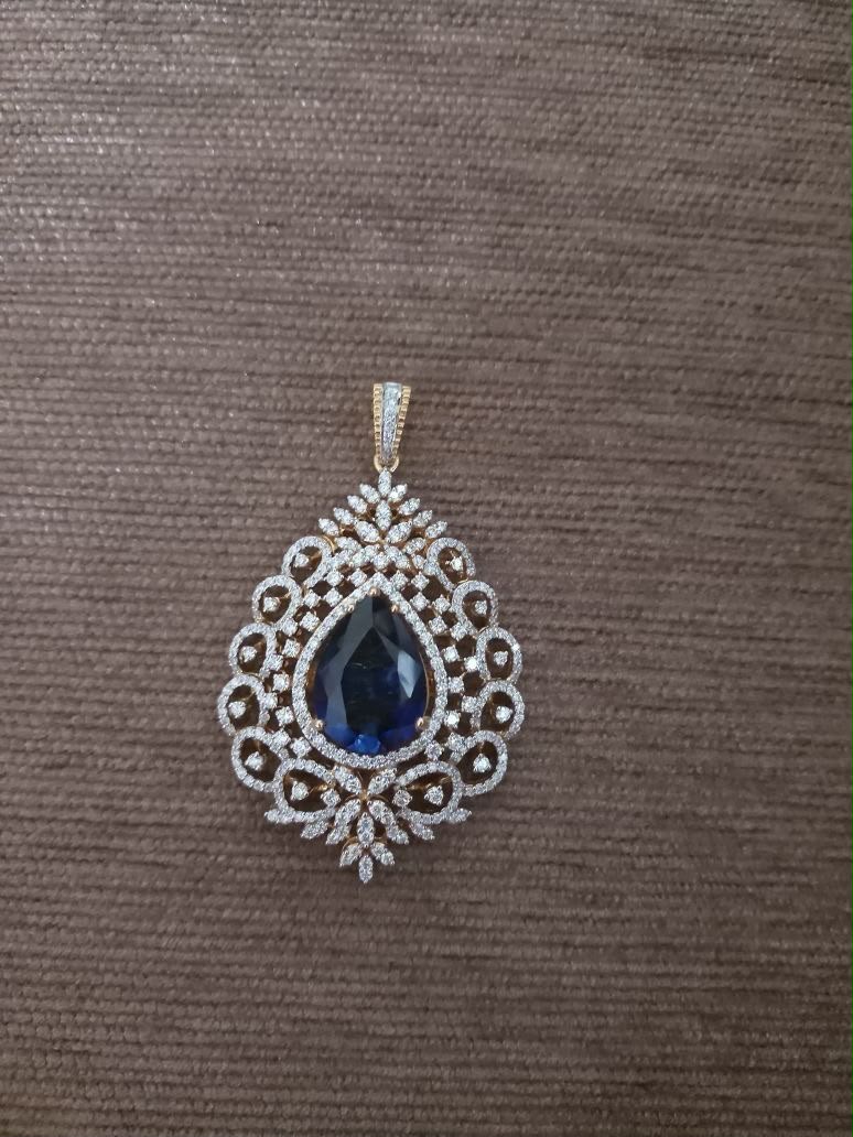 A standalone pendant with a blue-toned teardrop center in a pale frame.