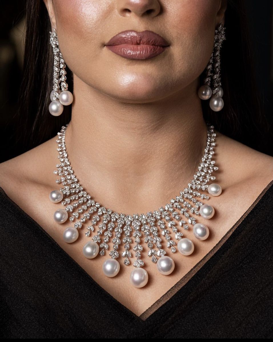 Necklace featuring a curved arrangement of pale round accents and hanging drops